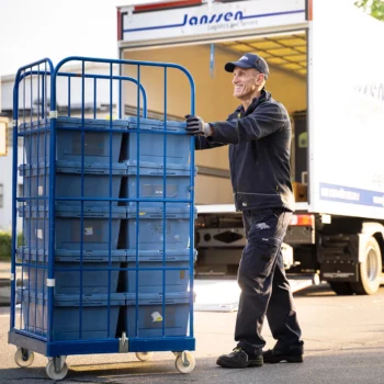 Ein Mitarbeiter von Janssen GmbH Logistics and Service liefert Arzneimittel aus. Ein LKW ist hinter ihm.